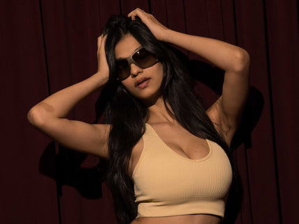 Woman in beige outfit posing against a dark background