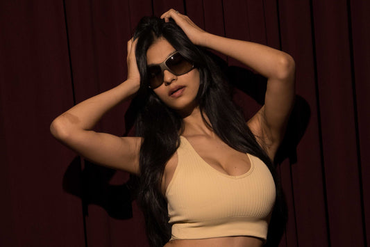Woman in beige outfit posing against a dark background